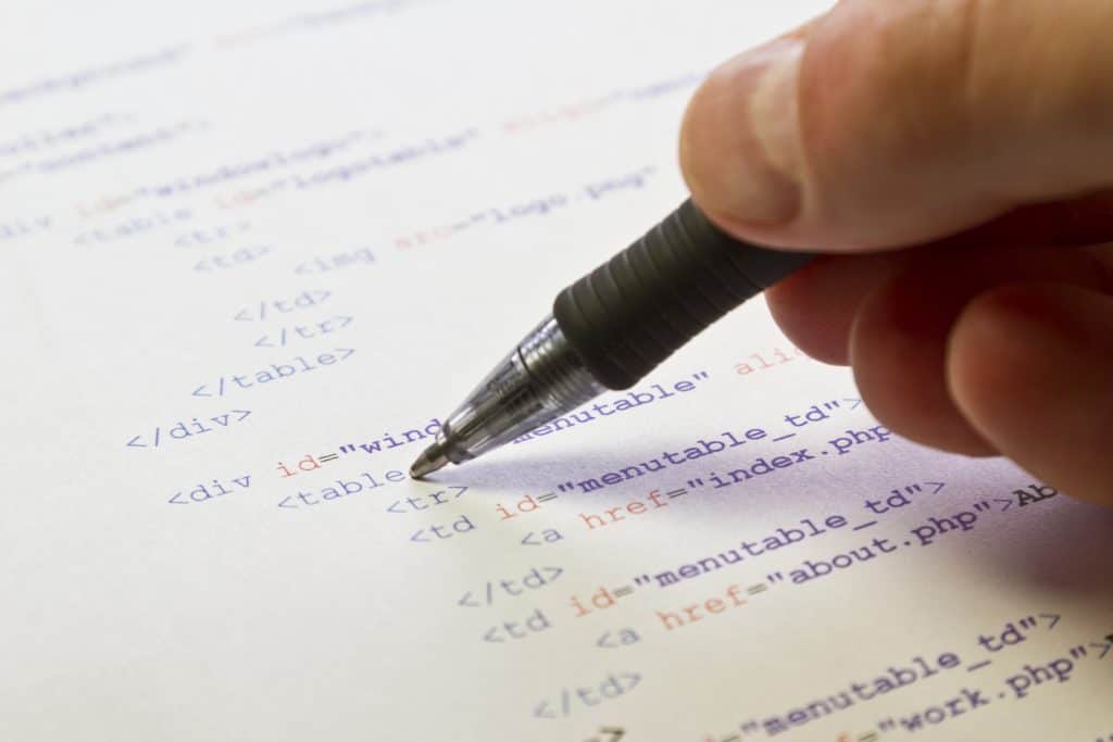 a programmer man pointing with his pen at html code for a web page SBI 302048274